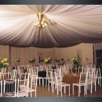 Salao de festas com cortinas, rebaixamento de teto e mesas de convidados